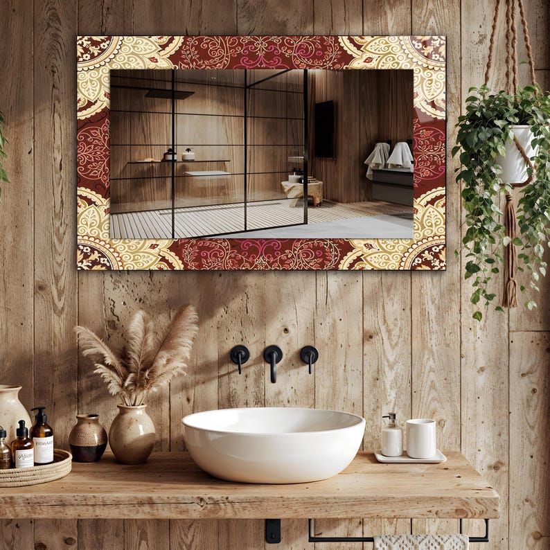 May include: A rectangular mirror with a decorative border featuring a repeating pattern in burgundy, cream, and gold tones. The mirror is mounted on a wooden wall above a white sink, with a view of a bathroom.