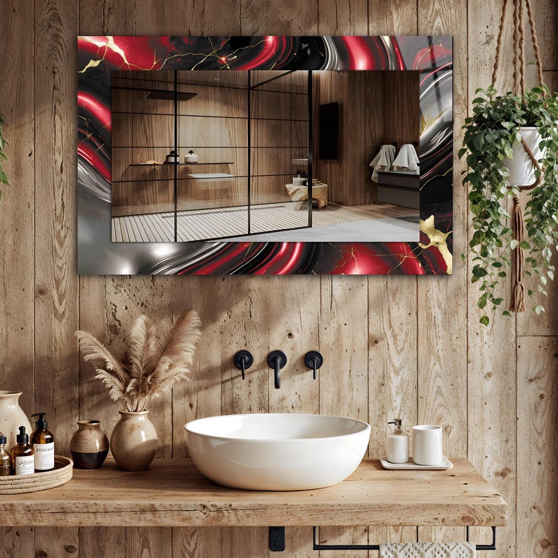 May include: A rectangular bathroom mirror with a decorative border featuring a red, black, and gold marbled design. The mirror reflects a bathroom with a wooden wall, a white sink, and a hanging plant.