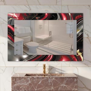 May include: Rectangular bathroom mirror with a decorative frame featuring a red, black, and silver abstract design with gold accents. The mirror reflects a modern bathroom with white fixtures and a glass shower.
