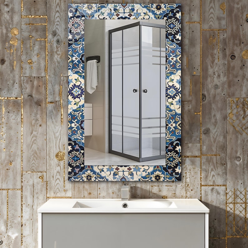K&ouml;nnte beinhalten: Rechteckiger Badezimmerspiegel mit dekorativem Rand mit blauem, wei&szlig;em und beigem Blumenmuster. Der Spiegel reflektiert eine Duschkabine mit schwarzem Rahmen und Milchglasscheiben, &uuml;ber einem grauen Waschtisch.