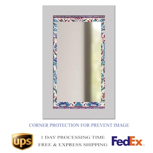 May include: Rectangular mirror with a white frame and a decorative border featuring floral patterns in blue, red, and white. The mirror's design includes a textured frame and a reflective surface.