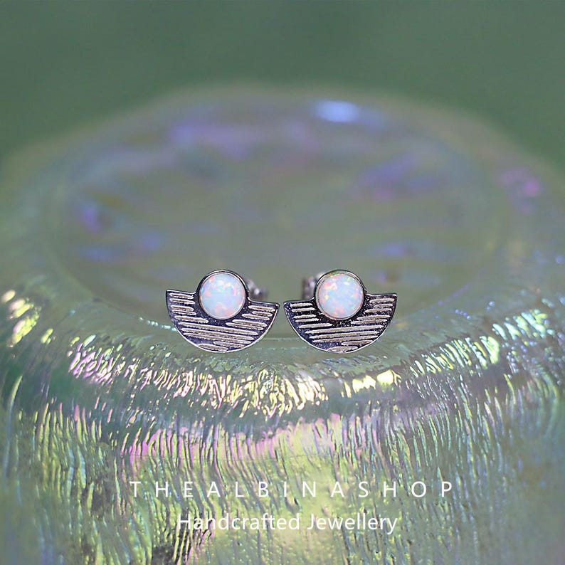 Puede incluir: Un par de pendientes de plata con una piedra de &oacute;palo blanco engastada en forma de media luna. Los pendientes est&aacute;n sobre un fondo blanco.