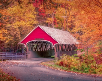 Op de afbeelding: Een rode overdekte brug met een houten frame en een bord met de tekst "Pennsylvannia River 1888" is omgeven door kleurrijk herfstblad.