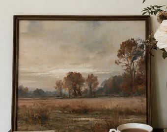 May include: A framed landscape painting depicting a field with trees under a cloudy sky, placed next to a dark blue ceramic vase filled with white flowers. A floral teacup and saucer sit on a stack of three books atop a wooden chest of drawers.