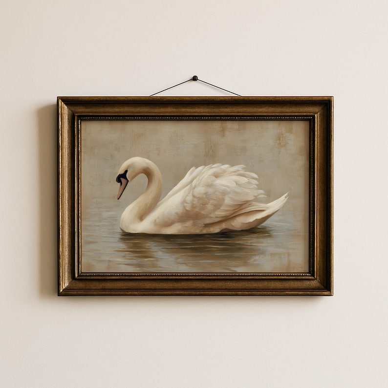 May include: A framed wall art piece featuring a painting of a white swan swimming on calm water. The swan has a long, curved neck and detailed feathers. The artwork is enclosed in a dark, ornate, metallic-toned rectangular frame with a black string.