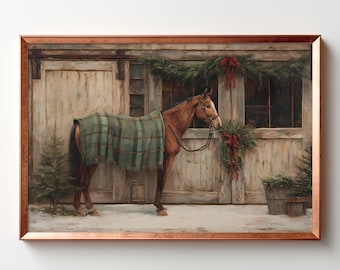 May include: A framed wall art print depicting a brown horse wearing a green plaid blanket standing in front of a rustic wooden barn door. The scene is decorated with evergreen garlands and red bows, with small pine trees on the snowy ground.