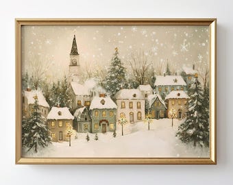 May include: A framed wall art print depicting a snowy winter village scene with houses, evergreen trees, and a tall clock tower. The illustration features soft warm light glowing from windows, a light dusting of snow, and falling snowflakes.