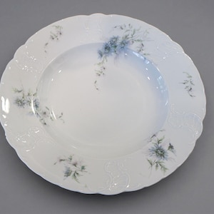 May include: White porcelain serving bowl with a scalloped edge and floral design. The bowl features delicate blue and green floral accents around the rim and in the center. The bowl has a classic, elegant design.