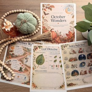 May include: A collection of educational activity sheets titled October Wonders, Senses Walk, Leaf Detective, and Build a Night Story, accompanied by a wooden bead garland with jute tassels and a textured sage green fabric pumpkin.