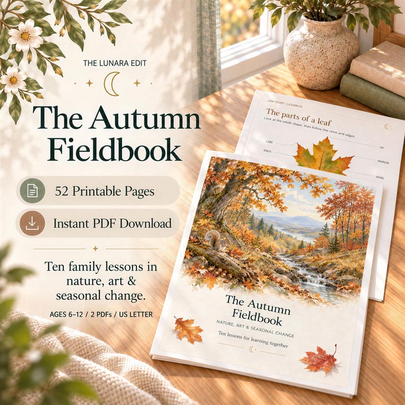A printed Autumn Fieldbook cover and leaf study page displayed on a wooden desk next to fallen autumn leaves.
