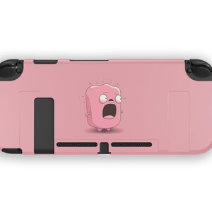 Könnte beinhalten: Eine rosa Nintendo Switch-Hülle mit einer Comicfigur auf der Vorderseite. Die Figur ist ein rosa Klecks mit einem überraschten Ausdruck und großen Augen.
