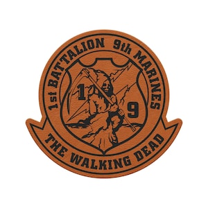 May include: A brown leather patch with the text "1st Battalion 9th Marines" and "The Walking Dead" in a circular design. The center features a grim reaper figure with a scythe and the numbers "1" and "9".
