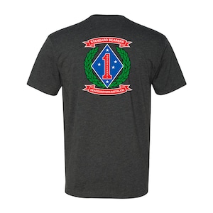 May include: A dark heather grey t-shirt with a red, white, and blue emblem on the back. The emblem features a blue diamond with a white star and the number "1" in red. The text "STANDARD BEARERS" and "HEADQUARTERS BATTALION" are in red and white.