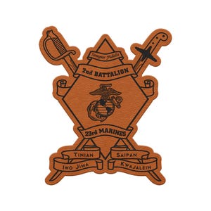 May include: A brown leather patch featuring the emblem of the 2nd Battalion, 23rd Marines. The design includes crossed swords, an eagle, globe, and anchor, and the words "Semper Fidelis." Ribbons display the names of battle locations.