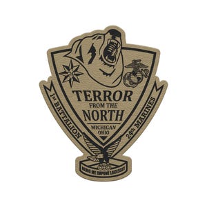 May include: A tan and black patch with the text "TERROR FROM THE NORTH" and "1st BATTALION 24th MARINES". The patch features a bear, a star, an eagle, and the Marine Corps emblem. The text "MICHIGAN OHIO" is also included.