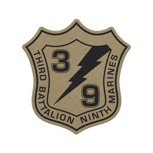May include: A tan and black Third Battalion Ninth Marines patch. The patch is shield-shaped with a black lightning bolt and the numbers "3" and "9". The words "THIRD BATTALION" and "NINTH MARINES" are printed around the edge.