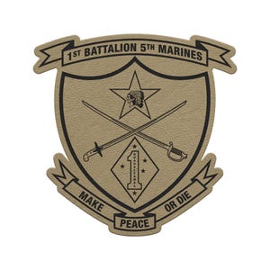 May include: A tan and black emblem featuring the text "1st Battalion 5th Marines" at the top. The emblem includes crossed swords, a star with a Native American headdress, and the words "Make Peace or Die".