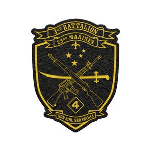 May include: A black and gold patch featuring the text "3rd Battalion 23rd Marines" in a banner. The patch has a shield shape with crossed rifles, stars, and the motto "Non Sibi Sed Patria" at the bottom. The number "4" is in a diamond shape.