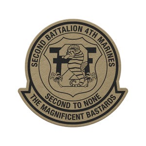 May include: A tan and black patch featuring the text "SECOND BATTALION 4TH MARINES" and "SECOND TO NONE THE MAGNIFICENT BASTARDS". The patch has a seahorse and palm trees in the center.