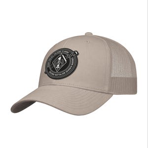 May include: Tan baseball cap with a mesh back and a curved brim. The cap features a circular patch with the text "READY FOR ALL YIELDING TO NONE!" and "SECOND BATTALION SEVENTH MARINES". The patch has a black border and a white and black design.