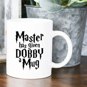 May include: White ceramic mug with black text that reads "Master has given Dobby a Mug" with lightning bolt accents.