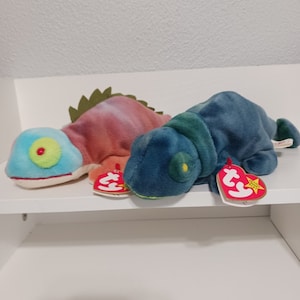 Puede incluir: Dos peluches Ty Beanie Babies, un camaleón azul y verde y un camaleón rojo y naranja, con sus etiquetas originales.