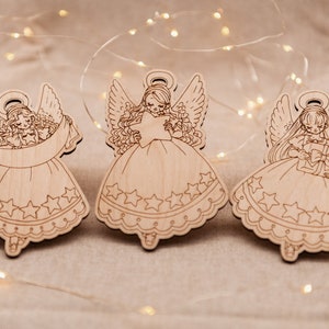 Peut inclure: Trois d&eacute;corations d'anges en bois avec des ailes, des halos et des d&eacute;tails en forme d'&eacute;toile. Chaque ange tient un objet diff&eacute;rent : une &eacute;toile, un rouleau et un coffret cadeau.