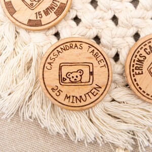 May include: A wooden token with the text "CASSANDRAS TABLET 25 MINUTEN" and a cartoon image of a bear on a tablet screen.