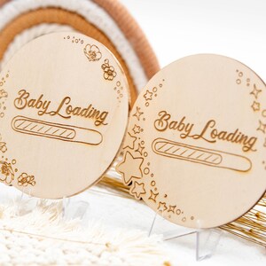 May include: Two wooden signs with the text "Baby Loading" and a progress bar. One sign is decorated with flowers and the other with stars.