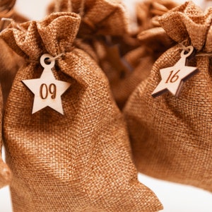 May include: Nine burlap gift bags with wooden star-shaped tags. The tags are numbered 09 and 16.