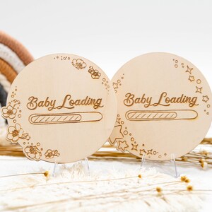 May include: Two wooden baby loading signs with a progress bar. One sign is decorated with flowers and the other with stars. Both signs are on small stands.