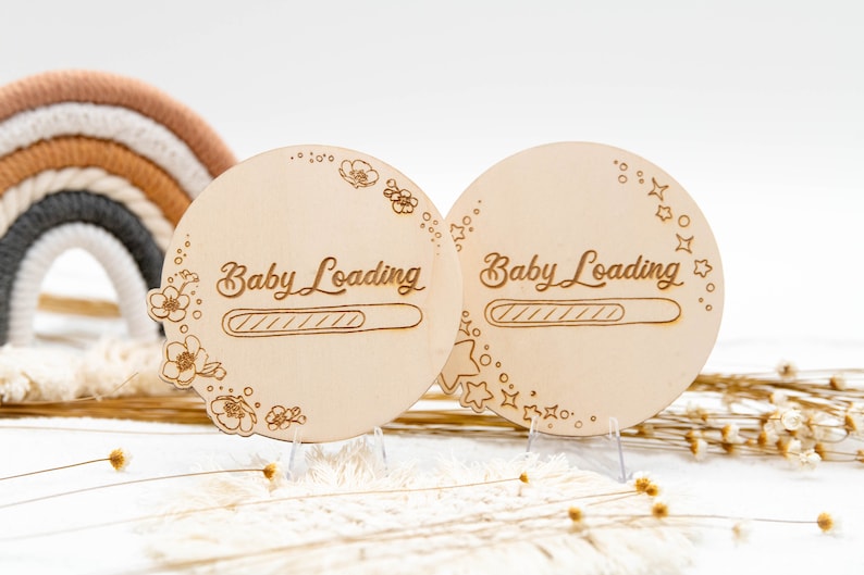 May include: Two wooden baby loading signs with a progress bar. One sign is decorated with flowers and the other with stars. Both signs are on small stands.