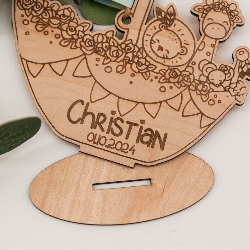 Puede incluir: Corte de madera de un m&oacute;vil para beb&eacute; con tem&aacute;tica de animales de la selva con una jirafa, un le&oacute;n y un rat&oacute;n. El m&oacute;vil est&aacute; personalizado con el nombre "Christian" y la fecha "01.10.2024".