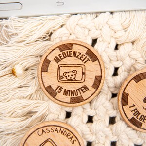 May include: Wooden tokens with engraved text and images. One token features a cartoon bear inside a phone screen with the text "MEDIENZEIT 15 MINUTEN". Another token features the text "7 FOLGE".
