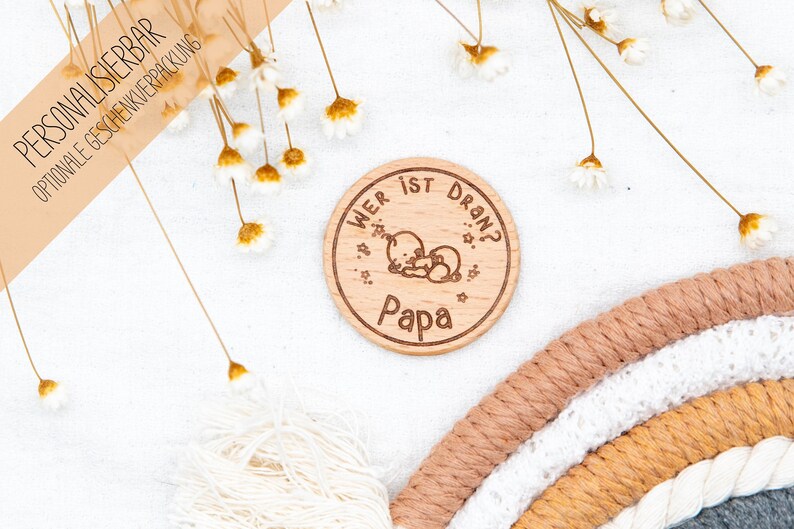 K&ouml;nnte beinhalten: Ein Holz-Kreis mit dem Text "Wer ist dran?" und dem Wort "Papa" darunter. Der Kreis hat eine kleine Illustration von zwei schlafenden B&auml;ren.