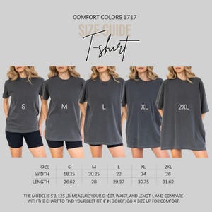 Puede incluir: Una gu&iacute;a de tallas para camisetas Comfort Colors 1717 que muestra cinco camisetas gris carb&oacute;n en tallas S, M, L, XL y 2XL. Una tabla enumera los anchos y largos en pulgadas para cada talla. El texto incluye la altura y el peso del modelo.
