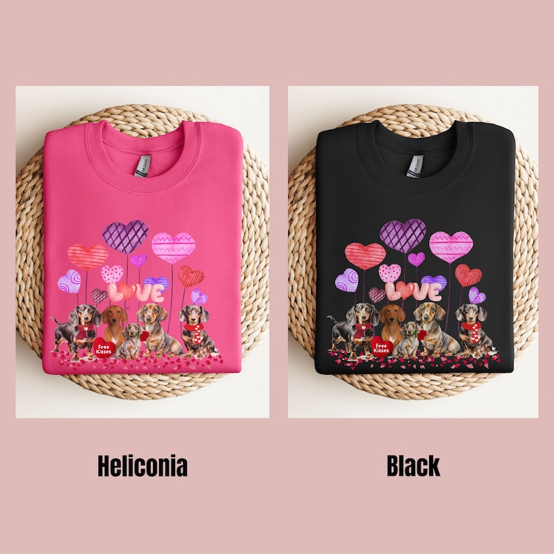 May include: Two sweatshirts, one pink and one black, each with a design of dachshunds, heart-shaped balloons, and the word "LOVE." The pink sweatshirt is labelled "Heliconia," and the black one is labelled "Black."