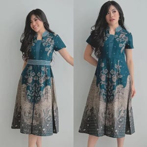 Può includere: Abito midi color teal con motivo floreale e paisley. L'abito presenta maniche corte, colletto alto e cintura abbinata. La gonna ha un design svasato con uno spacco frontale.