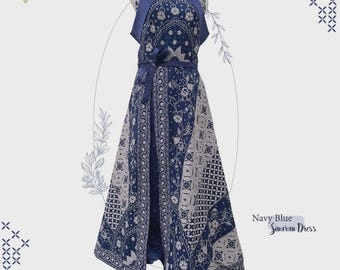 May include: Navy blue Sinaran dress with a unique batik pattern. The dress features a halter neckline, a matching belt, and a split front. The dress is adorned with floral and geometric designs, and the text "Exotik Batik" is visible.