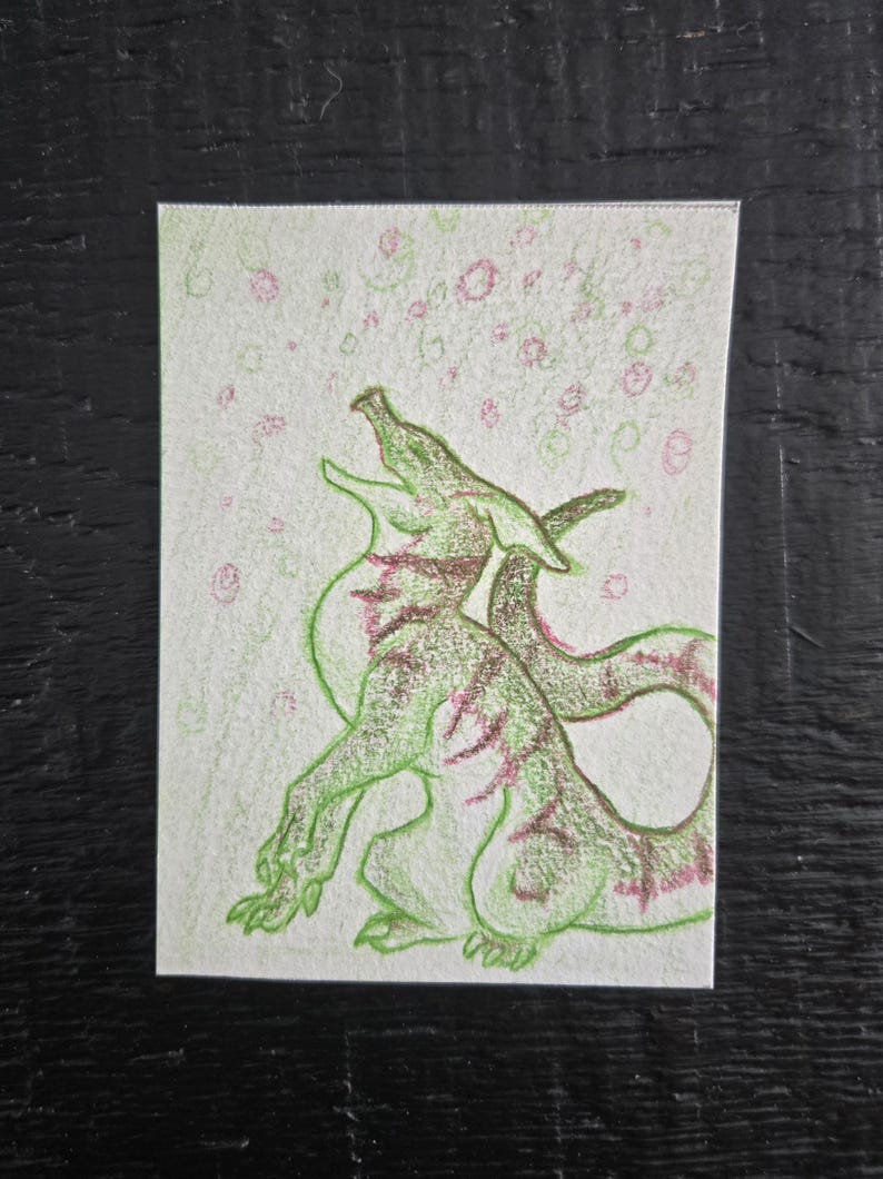 Op de afbeelding: Handgetekende illustratie van een groene draak met roze accenten op een witte achtergrond. De draak staat in een dynamische pose, met open mond en een gekrulde staart. Roze en groene bellen zweven boven de draak.