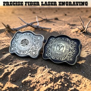 May include: Two metal belt buckles with intricate engraved designs. One is silver with an American flag and the name "Jason", the other is black with a bull skull and the word "Cowboy". The text "PRECISE FIBER LASER ENGRAVING" is at the top.
