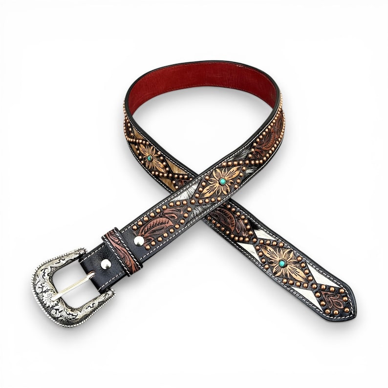 May include: Black leather belt with floral and leaf tooling, turquoise accents, and a silver buckle. The belt features a red leather interior and is adorned with small metal studs. A stylish western accessory.