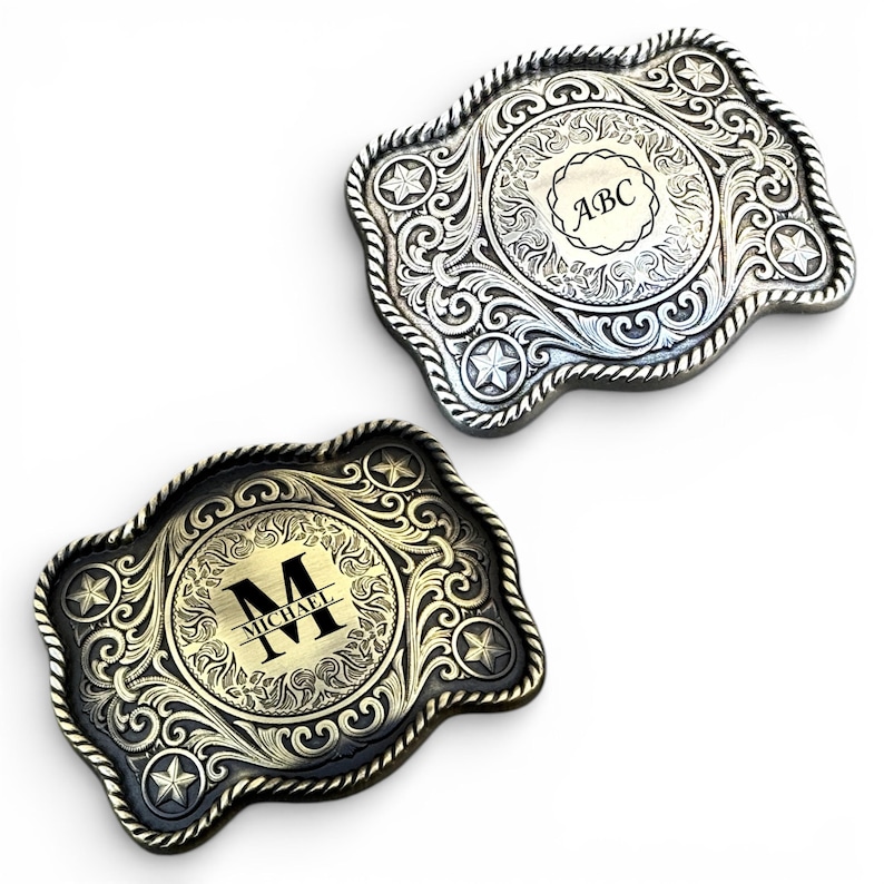 May include: Two decorative metal belt buckles. One is silver with the initials "ABC" and the other is gold with the initial "M" and the name "Michael". Both buckles have a detailed floral and star design.