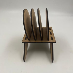 May include: Wooden coaster holder with four round coasters. The holder is made of brown wood and has a simple design.