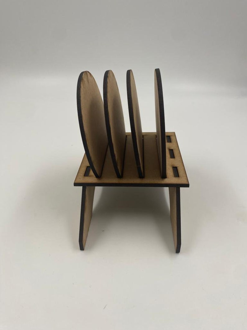 May include: Wooden coaster holder with four round coasters. The holder is made of brown wood and has a simple design.
