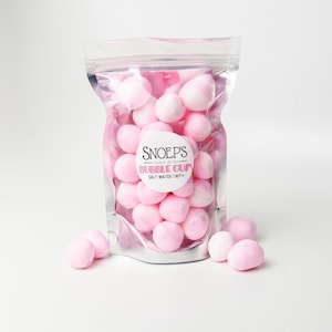 May include: A silver resealable bag filled with pink freeze-dried salt water taffy. The bag has a label that reads "Snoep's Freeze Dried Bubble Gum Salt Water Taffy".