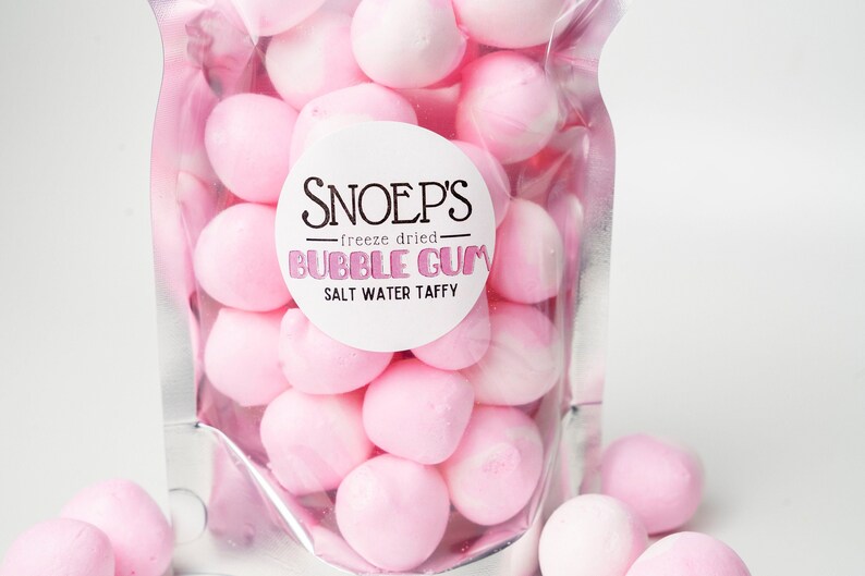 May include: A clear plastic bag filled with pink freeze-dried bubble gum salt water taffy. The bag has a white label with the text "Snoep's - freeze dried - Bubble Gum Salt Water Taffy".