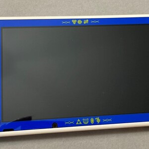 Puede incluir: Una consola Nintendo Switch blanca con un dise&ntilde;o tem&aacute;tico azul y dorado. La consola tiene una pantalla azul y un marco blanco. La consola est&aacute; acompa&ntilde;ada por dos mandos azules y morados con detalles dorados.