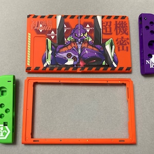 Pode incluir: Um conjunto de peças de reposição laranja e verde para Nintendo Switch. O conjunto inclui uma placa frontal com um gráfico de um robô da série de anime Neon Genesis Evangelion, uma placa traseira, um joy-con esquerdo e um joy-con direito.