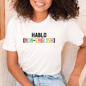 May include: White t-shirt with the text "HABLO [NON-ENGLISH]" printed in black and colorful letters.